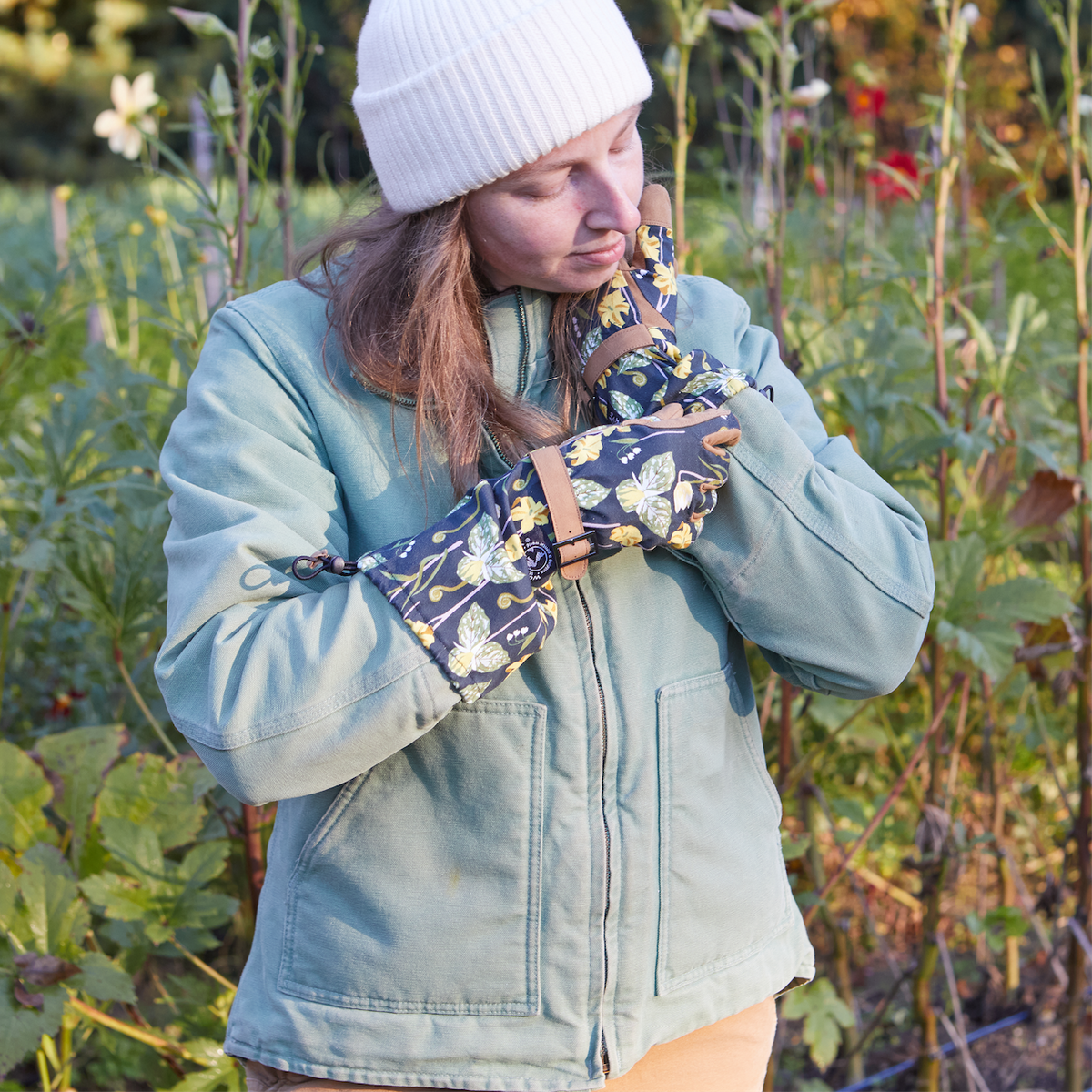 Barking Gardener Arm Saver Gloves with floral print, long cuffs, and synthetic leather palms worn in a garden.