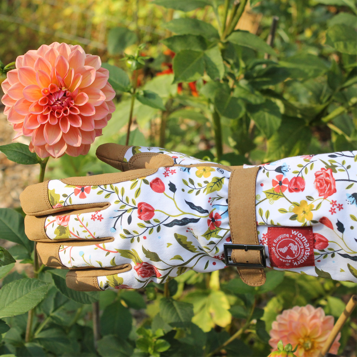 Barking Gardener Arm Saver gloves with floral print, long cuffs, and tan synthetic leather palms near a dahlia flower.