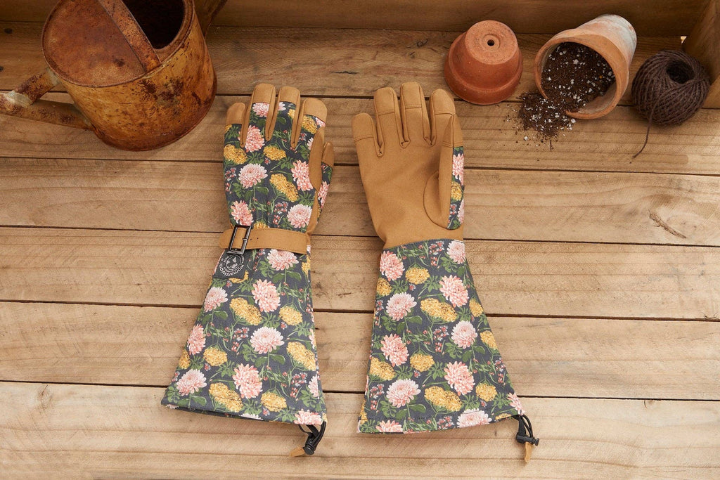 Barking Gardener Arm Saver Gloves with floral print, extra-long cuffs, and tan synthetic leather palms on wood table.