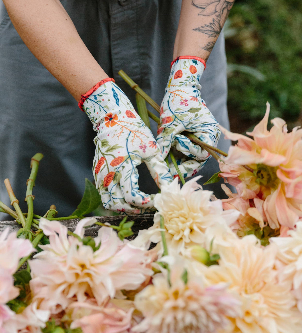 Barking Gardener floral patterned nitrile gardening gloves worn while arranging fresh dahlia flowers in a garden.